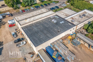 aerial view of commercial building roof with cars and trucks in parking lot