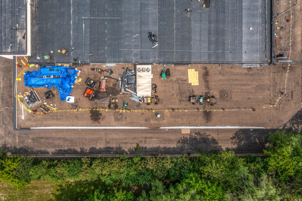 Arial view of commercial building with roofing crew replacing the roof.